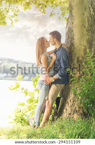 Couple in love on the lake, beneath the trees, kissing