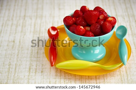 Strawberries in Teal Bowl on a Yellow plate with Three Spoons