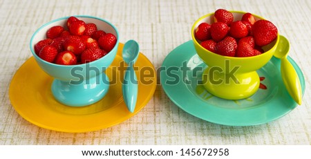 Strawberries in Yellow and Teal Bowls on Plates with Spoons