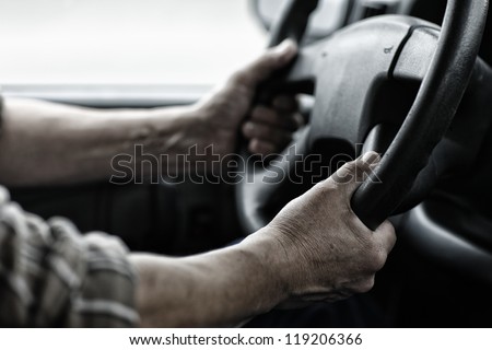 Male driver hands holding steering wheel.