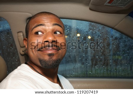 Cute smiling African American man driving car
