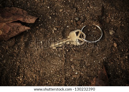 Metal key lost and found on soil ground.