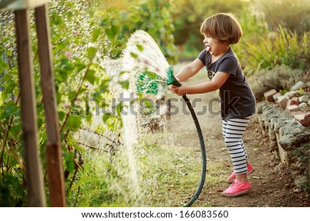 Little happy girl watering garden