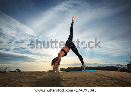 Woman Practicing Yoga Outdoors Over Sunset Sky Background.