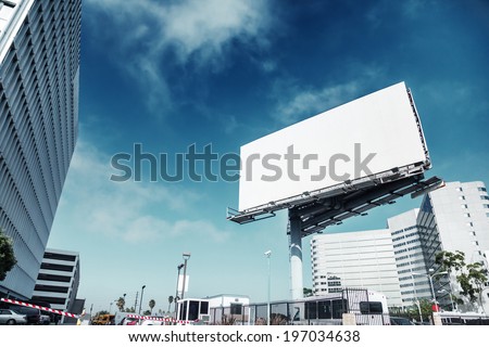 Big white blank billboard in modern city over blue sky background.