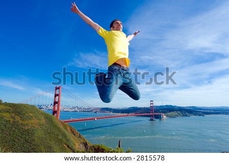 Happy young man jumping high in the air next to the Golden Gate bridge, San Francisco, California