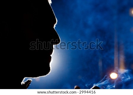 Man\'s face silhouette at night, dramatic light, close-up.