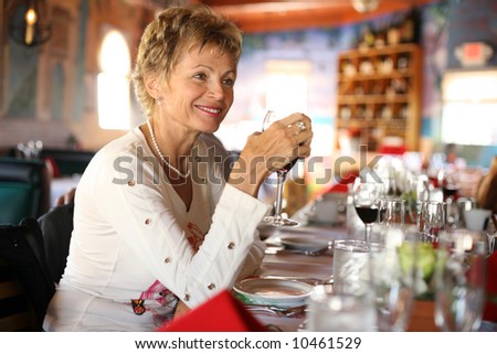 Happy mature woman with glass of wine in a restaurant at party