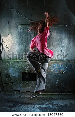 Girl dancing on a street next to old grungy wall