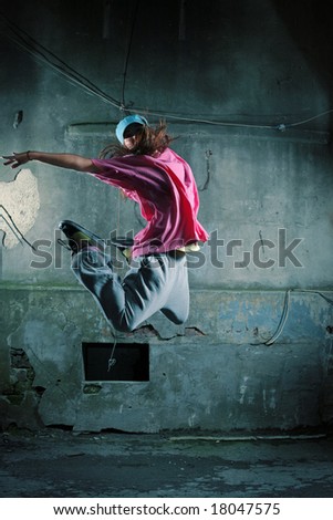 Girl dancing on a street next to old grungy wall