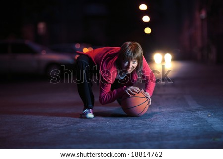 Young woman with basketball ball on night street