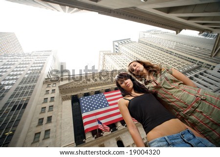 Two young women near New York Stock Exchange. Wide angle portrait.