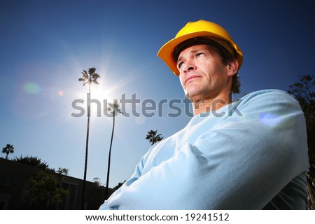 Construction worker in yellow hard hat over blue sunny sky