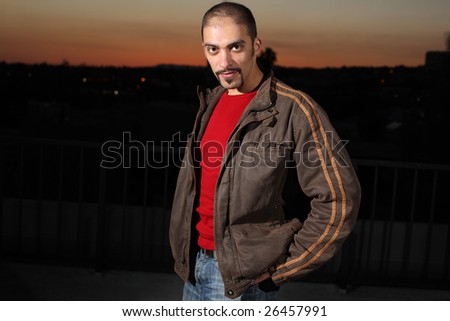 Portrait of a handsome young man in brown jacket standing outdoors