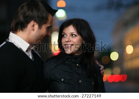 Beautiful young couple walking together in night city. Shallow DOF.