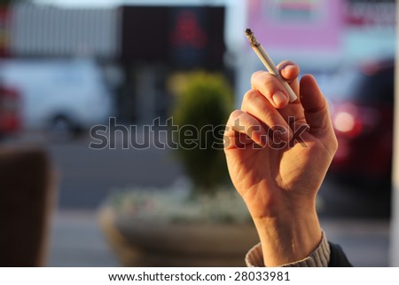 Hand with smoking cigarette. Close-up, shallow DOF.