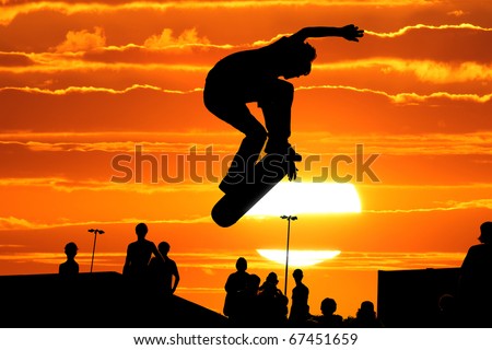 Jumping skateboarder silhouette over scenic sunset sky background