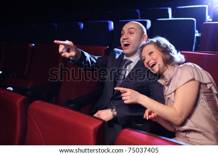 Young couple in cinema movie theater laughing while watching comedy show.