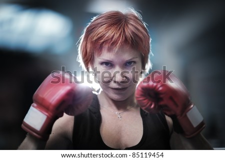 Portrait of mature woman in boxing gloves looking at camera. Closeup.