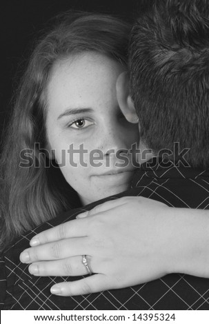 young engaged woman with arms around shoulders of man