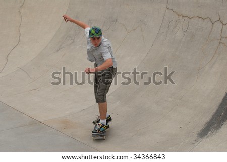 teenage skateboarder riding in cement half pipe