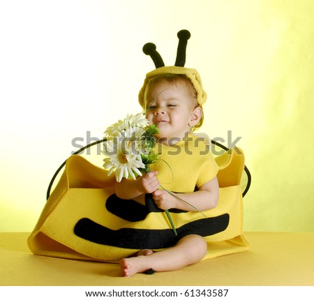 one year old child dressed up like a bee on yellow background