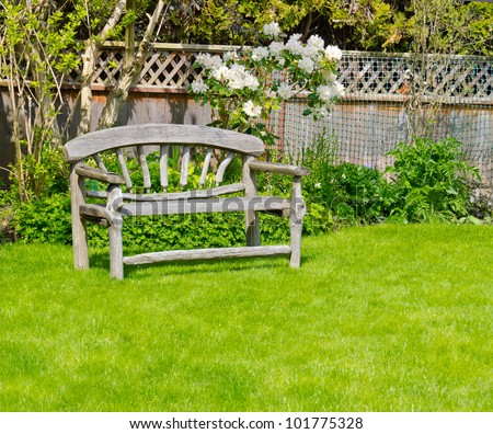 Wooden bench designed in country style on green grass back yard.