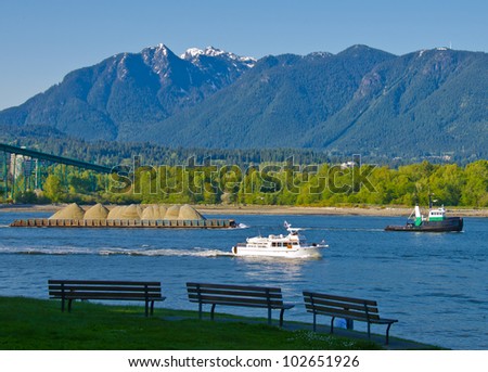 Busy looking inlet in a sunny day with motor yacht ( boat ) and a tug boat, towing barge. Vancouver, Canada.