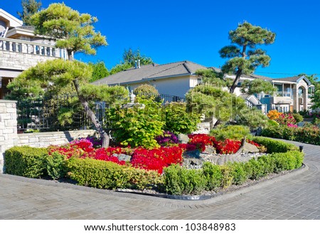 Landscape design. Nicely trimmed bushes and colorful garden in front of the house.