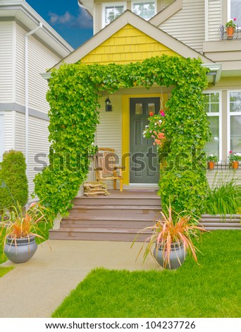 Great looking house entrance with ivy around the columns and hand made chair on the porch