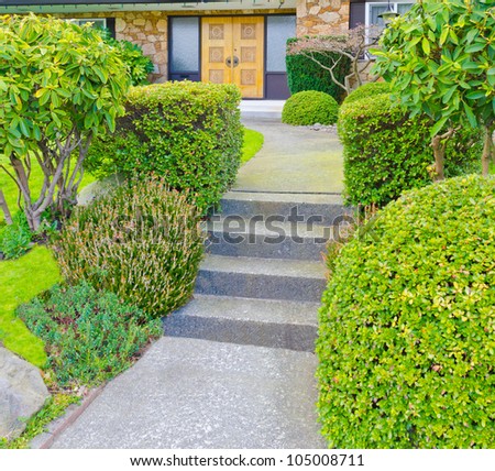 House entrance with nicely trimmed bushes.