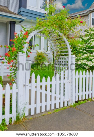 Arch wooden entrance with the fence, wreathed with flowers
