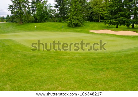 Nice looking golf course with a bunker and blue flag