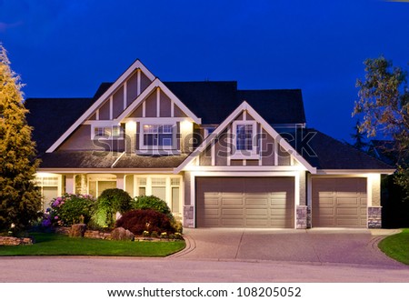 Big luxury house with triple garage doors at dusk, night in suburbs of Vancouver, Canada