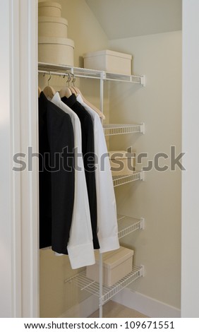 Men garments and some boxes ( clothing, wear ) on a pole and shelves in the closet. Interior design.
