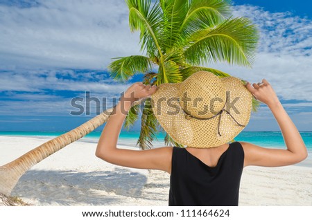 Traveler, tourist  woman looking at the palm tree over caribbean sand beach