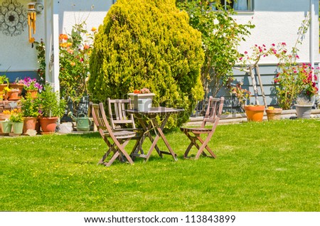 Two wooden country style lawn chairs and the table at the front   ( back ) yard.