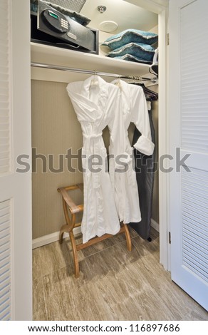 Two bathrobes on a pole and shelves with the safe box in the closet. Interior design.