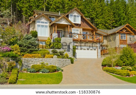Big custom made luxury house on the rocky slope with nicely landscaped front yard in the suburbs of North Vancouver, Canada.