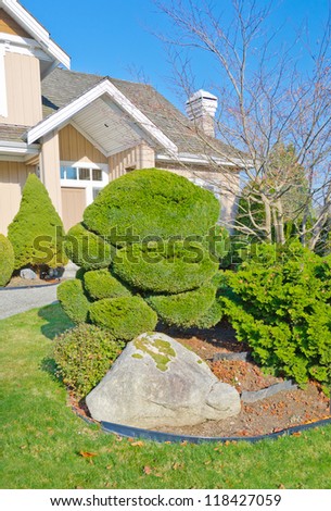 Nicely trimmed bushes and stones, rocks at the front yard. Landscape design.