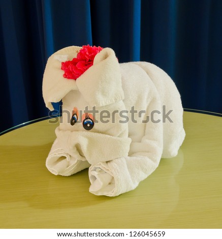 White spa towel twisted ( has been folded out of a towel )  in the form of a puppy, dog. Decorated with flowers.