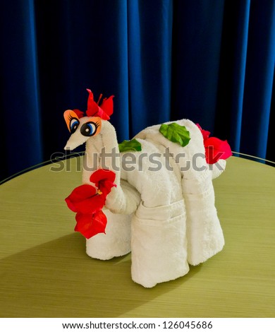 White spa towel twisted ( has been folded out of a towel )  in the form of an abstract animal, dinosaur. Decorated with flowers.