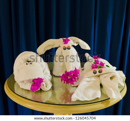 Group, pack of  animals made from white spa towels twisted ( has been folded out of a towel )  in the different forms form such as  a abstract creature, elephant and scorpion. Decorated with flowers.