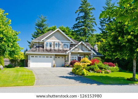 Big custom made triple doors garage luxury house with nicely landscaped front yard in the suburbs of Vancouver, Canada.
