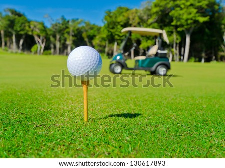 Golf Ball On The Tee With The Golf Cart Out Of The Focus As A Background..