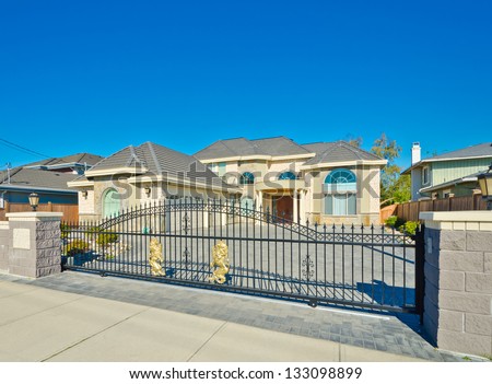 Big custom made triple doors garage luxury house behind the gates and nicely paved driveway in the suburbs of Vancouver, Canada.