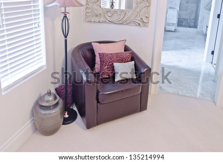 Leather chair with some pillows, floor lamp and the decorative pot in the corner of the room. Interior design.