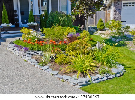 Nicely decorated flower bed, some flowers and nicely trimmed bushes on the front yard. Landscape design.