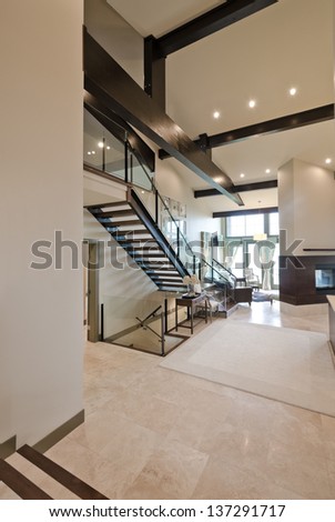 Outlook at the luxury spacious  modern room with the  fireplace and stairs to the upper level. Interior design. Vertical.