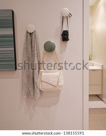 Some decorations hanging on the wall hooks. Scarf, kerchief, bag, pouch and photo camera. Interior design. Fragment.